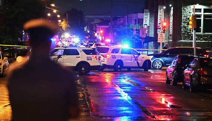 Police vehicles and personnel can be seen while at the scene after a mass shooting in Philadelphia on July 3, 2023. — AFP