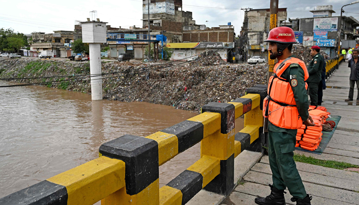 Rescue workers monitor the flood situation at a bridge over a stream in Rawalpindi on July 7, 2023. — AFP