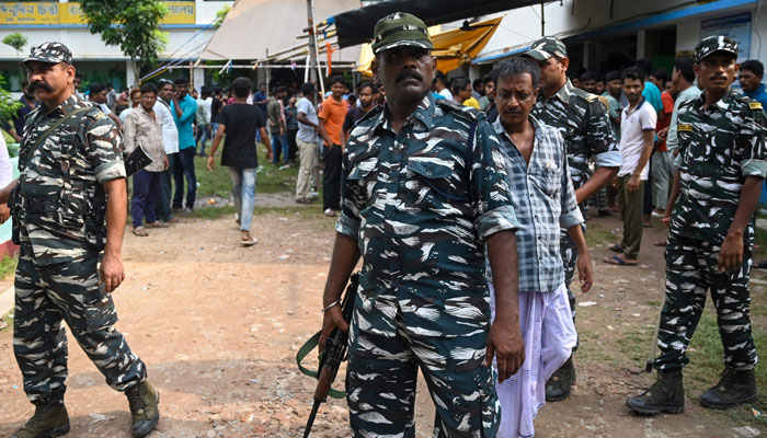 Paramilitary soldiers stand guard as people queue at a polling station to cast their votes in West Bengal’s ‘Panchayat’ elections held on the outskirts of Kolkata on July 8, 2023. — AFP