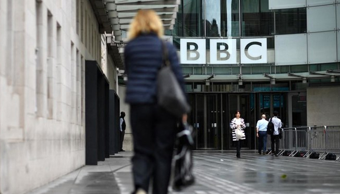 Pedestrians walk past a BBC logo. — AFP