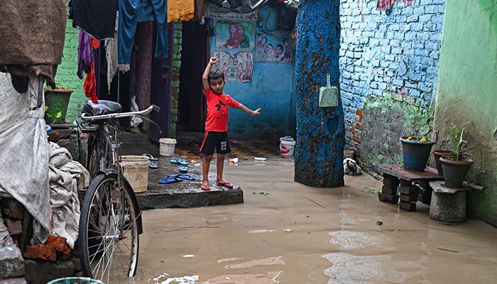 A boy stands outside his flooded house near the banks of Yamuna River after it overflowed due to monsoon rains, in New Delhi on July 11, 2023. — AFP