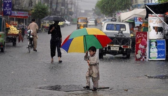 A child carries an umbrella as he walks on the road during rain. — AFP