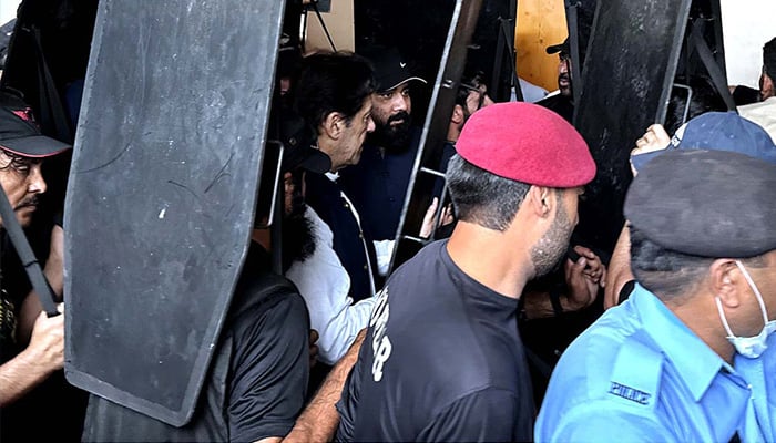 Security personnel with ballistic shields escort former prime minister Imran Khan as he leaves from Islamabad High Court on May 31, 2023. — APP