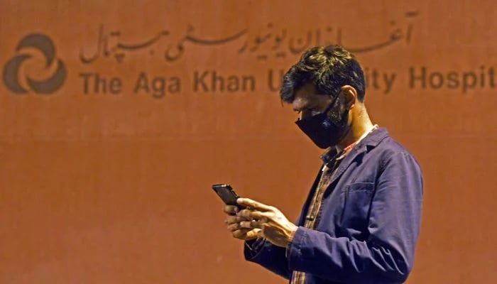 A man is seen using his mobile phone outside the Aga Khan University Hospital in Karachi, on February 26, 2020. — AFP