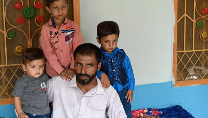 In this picture taken on July 18, 2023, Pakistani worker Muhammad Naeem Butt sits with his children at his home in Khuiratta. — AFP