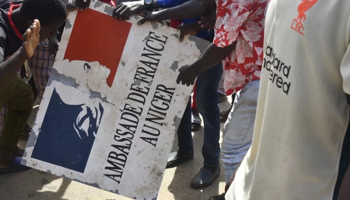 Protestors destroying a name plate that translates to Embassy of France for Niger outside the French embassy in Niger, on  30 July 2023. — AFP/File