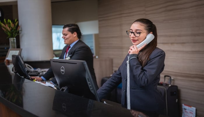 This representational picture shows hotel staff working behind the reception desk. — Unsplash/File