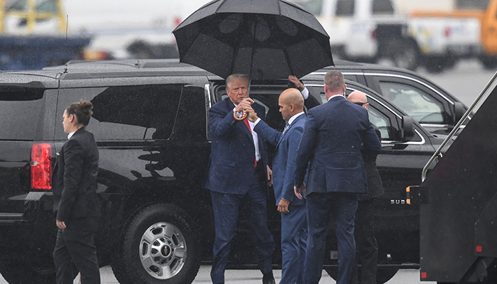 Former US President and 2024 hopeful Donald Trump grabs an umbrella as he arrives to Ronald Reagan Washington National Airport in Arlington, Virginia, on August 3, 2023. — AFP