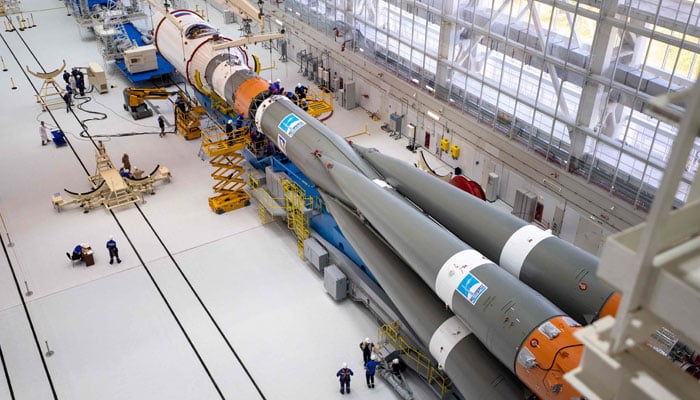 This handout photograph taken and released by the Russian Space Agency Roscosmos on August 7, 2023, shows technicians finishing assembling a Soyuz 2.1b rocket carrying the Luna-25 lander at the Vostochny cosmodrome. — AFP