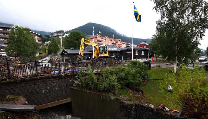 An excavator clears debris after the Susa River running through Are, northern Sweden, overflowed following heavy rainfall due to extreme weather ´Hans´ on August 8, 2023. — AFP