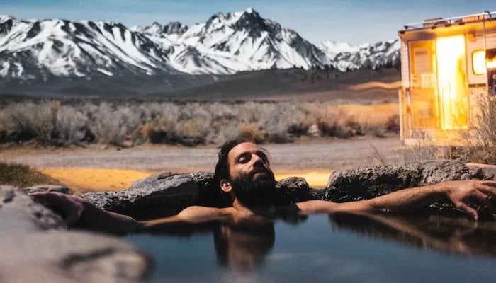 A representational image shows a man taking a cold plunge into a rocky pool. —Unsplash