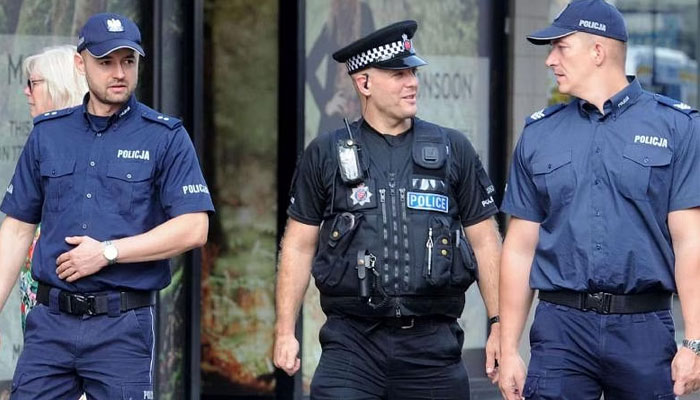 Three Polish police officers walk together on a street. — AFP/File