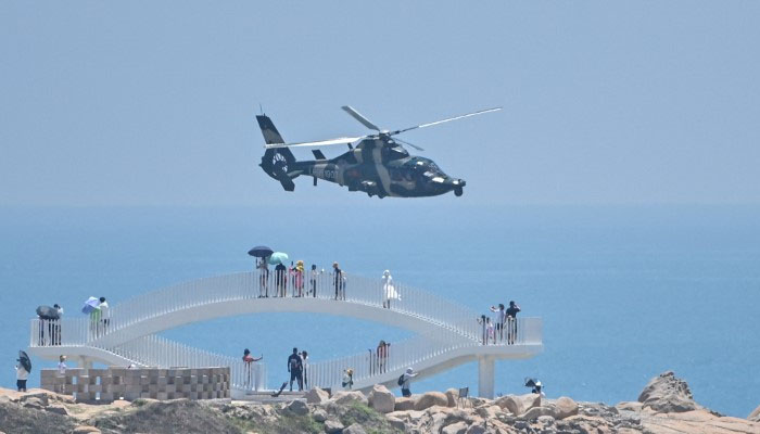 Tourists look on as a Chinese military helicopter flies past Pingtan Island, Taiwan in this undated image. — AFP/File