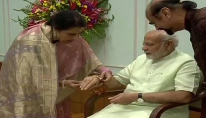 Qamar Mohsin Shaikh tying rakhi to Modi. — Twitter/@business_today