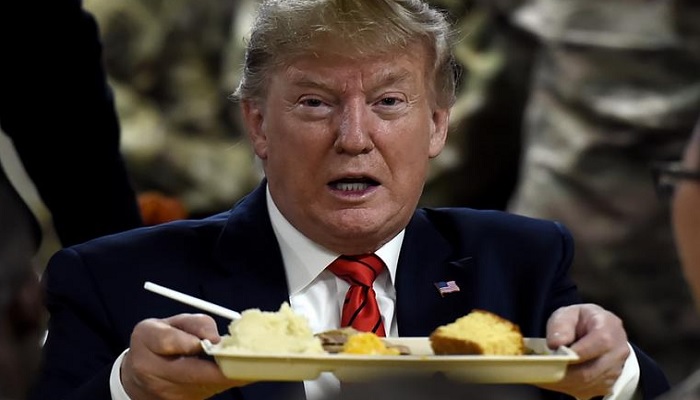 Former US president Donald Trump holds out a tray of food. — AFP/File