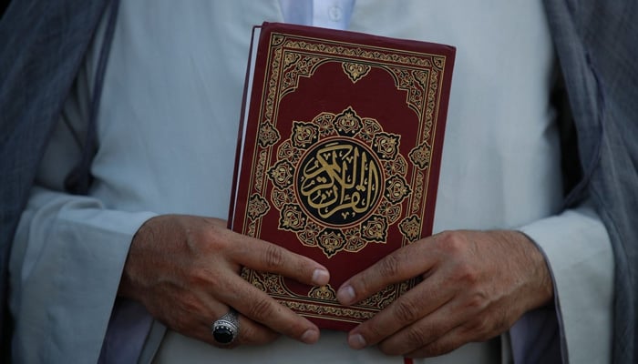 A cleric holds the Holy Quran outside the Swedish embassy in Baghdad, Iraq, June 30, 2023. — AFP