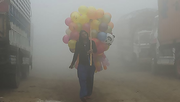 A Pakistani vendor carries balloons down a Lahore street amid heavy smog. — AFP/File