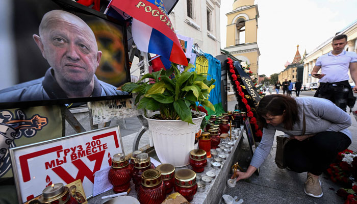 A woman lays a candle at a makeshift memorial for the late head of the Wagner paramilitary group, Yevgeny Prigozhin in Moscow, on August 27, 2023.— AFP