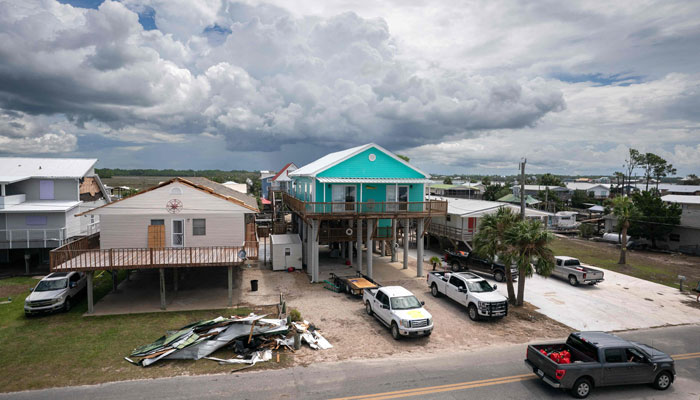 A motorist passes storm damaged houses in the aftermath of Hurricane Idalia on August 31, 2023 in Keaton Beach, Florida. Idalia, which weakened to a tropical storm made landfall at Keaton Beach, Florida as a category 3 hurricane and caused heavy rain and flash flooding. AFP