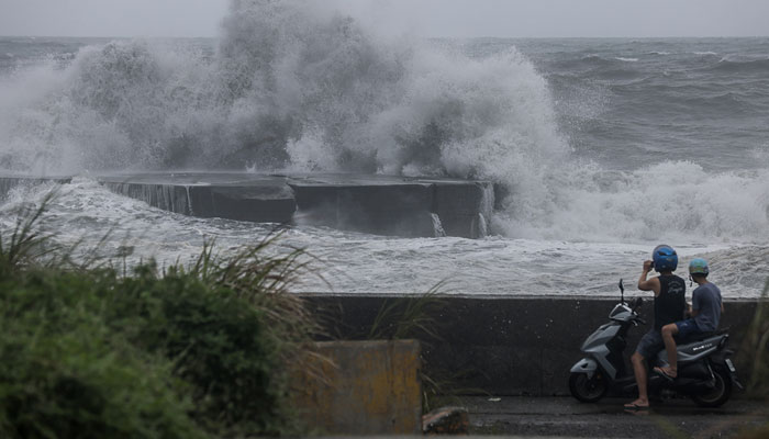 People watch huge waves in Yilan as Typhoon Haikui makes landfall in eastern Taiwan on September 3, 2023. — AFP