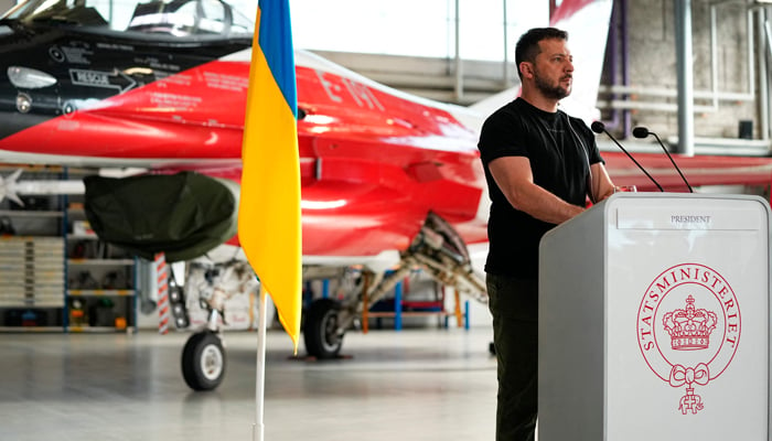 Ukrainian President Volodymyr Zelensky addresses a press conference in front of an F-16 fighter jet in the hangar of the Skrydstrup Airbase in Vojens, northern Denmark, on August 20, 2023. — AFP