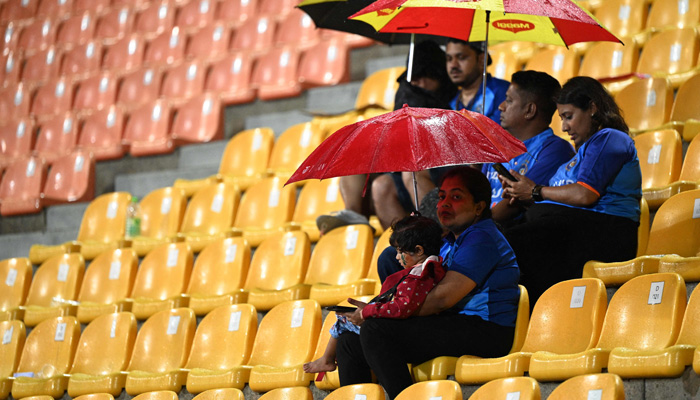 Indian fans wait out a rain delay during the Asia Cup 2023 one-day international (ODI) cricket match between India and Pakistan at the Pallekele International Cricket Stadium in Kandy on September 2, 2023. -AFP