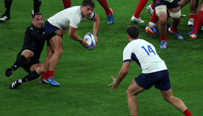 Frances scrum-half and captain Antoine Dupont (C) is tackled by New Zealands scrum-half Aaron Smith (L) as he passes the ball to Frances right-wing Damian Penaud (R) during the France 2023 Rugby World Cup Pool A match between France and New Zealand at the Stade de France in Saint-Denis, on September 8, 2023. — AFP