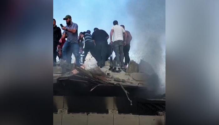 Palestinians celebrating on top of an Israeli tank in Palestine, on  October 7, 2023, in this still taken form a video. — X/@AlArabiya_Eng