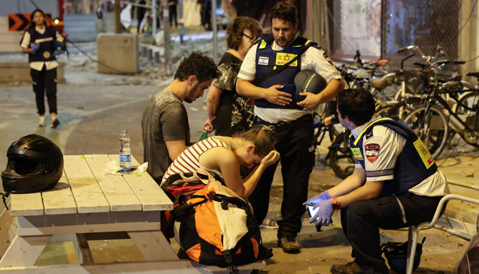 A young woman reacts as she speaks to Israeli rescuers in Tel Aviv after she was hit by a rocket fired from Gaza Strip on October 7, 2023.  — AFP