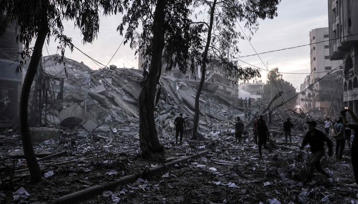 People walk atop the rubble of a tower destroyed in an Israeli air stike in Gaza City on October 7, 2023. — AFP