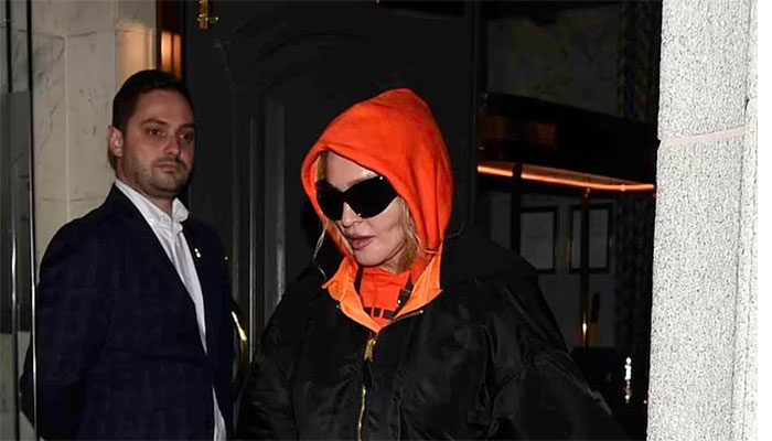 Madonna cut a low key figure as she exited the swanky Stock Exchange hotel in oversized orange hoodie.