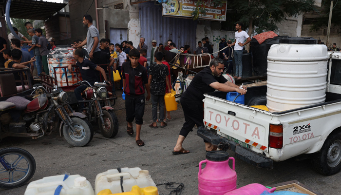 Palestinians queue to refill on water in Rafah refugee camp in the southern Gaza Strip, on October 14, 2023. — AFP