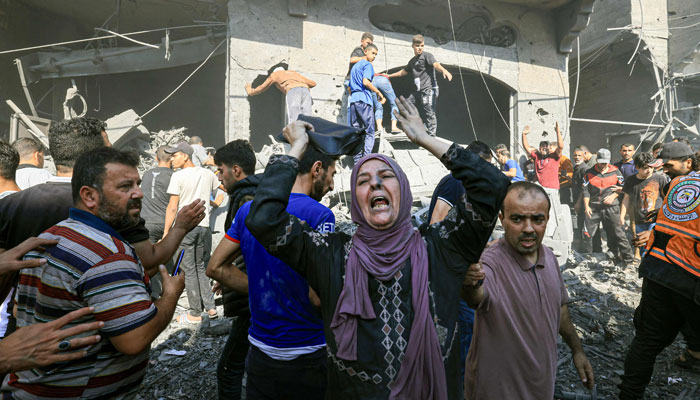 A Palestinian woman reacts as others rush to look for victims in the rubble of a building following an Israeli strike in Khan Yunis in the southern Gaza Strip on October 17, 2023. — AFP