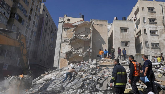 People search for victims under the rubble of a destroyed building in Gaza Citys Rimal residential district on Sunday, following Israeli airstrikes. — AFP