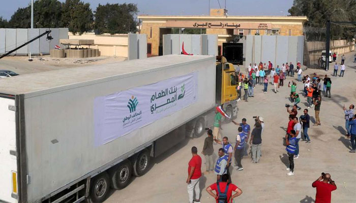 People on the Egyptian side of the Rafah border crossing watch as a convoy of lorries carrying humanitarian aid crosses to the Gaza Strip, October 22, 2023. — AFP