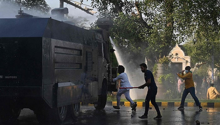 Pakistan Tehreek-e-Insaf (PTI) party activists and supporters of former Pakistan´s Prime Minister Imran hit a police water cannon vehicle during a protest against the arrest of their leader in Lahore on May 9, 2023. — AFP