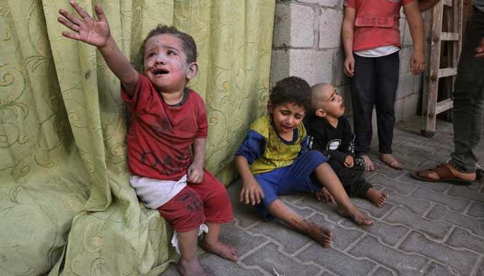 Palestinian children covered in dust from an Israeli air strike sit in the grounds of a hospital in Rafah, in the southern Gaza Strip on October 23, 2023, amid the ongoing battles between Israel and Palestine. — AFP