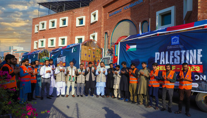 A group of Al Khidmat Foundation workers praying in front of trucks carrying aid and relief for Gaza victims. — Al Khidmat Foundation