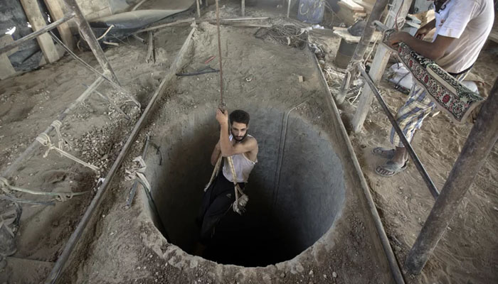 A Palestinian man is lowered into a smuggling tunnel that runs beneath the Egypt-Gaza Strip border, on Sept. 11, 2013. — AFP
