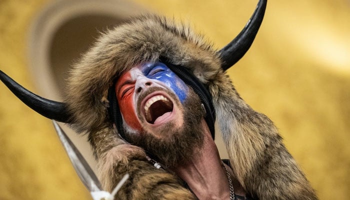 Jacob Chansley, known as the QAnon Shaman, inside the US Senate chamber after the US Capitol was breached by a mob during a joint session of Congress on Jan 6, 2021, in Washington, DC. — X/@winmcnamee