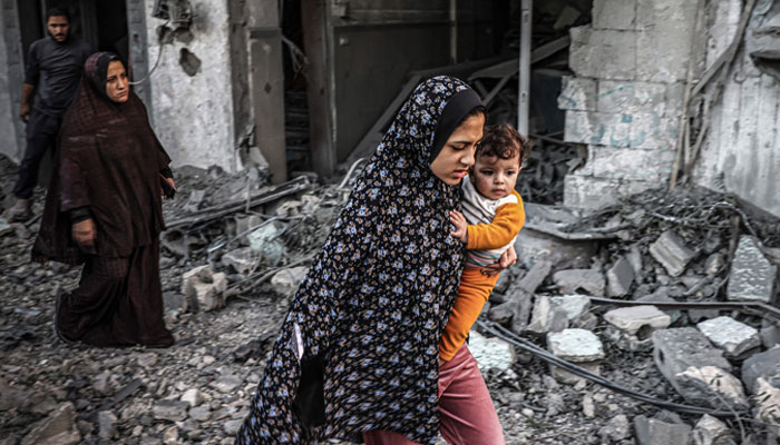 A woman holding a child flees following an Israeli strike in Rafah in the southern Gaza Strip on November 23, 2023. — AFP