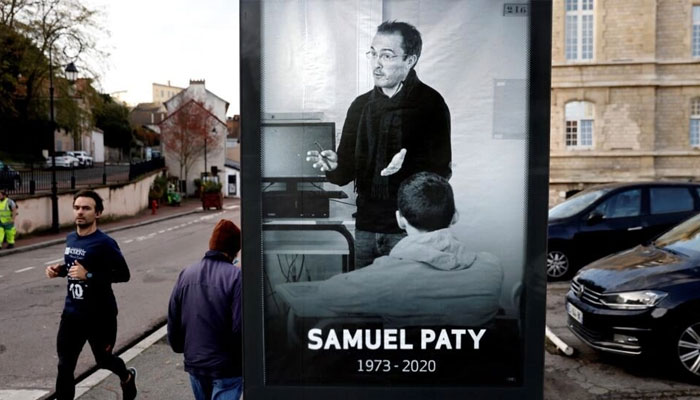 Pedestrians pass a poster depicting French teacher Samuel Paty placed in the city centre of Conflans-Sainte-Honorine, 30km northwest of Paris, November 3, 2020. — AFP File