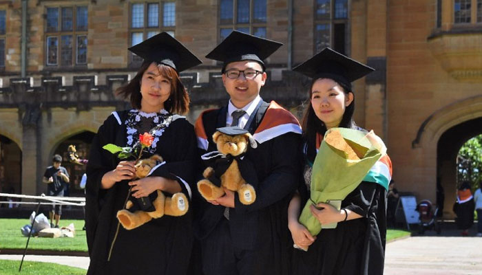 Students from China pose for family photos after graduating from the University of Sydney in Sydney, Australia, in 2017. — AFP