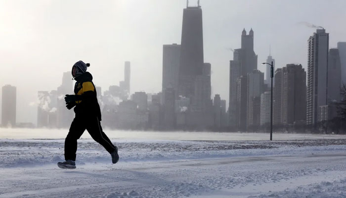 A jogger runs along Lake Michigan at sunrise as temperatures hover about -8 degrees on Dec. 22, 2022, in Chicago, Illinois. — AFP