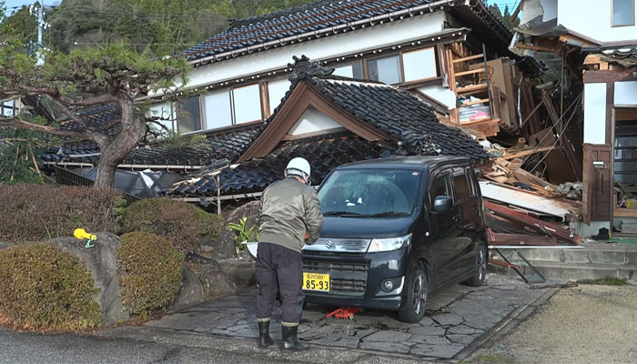 This screen grab from AFPTV video footage taken on January 2, 2024, shows a man standing in front of a damaged house in Wajima, Ishikawa prefecture, a day after a major 7.5 magnitude earthquake struck the Noto region in Ishikawa prefecture. — AFP