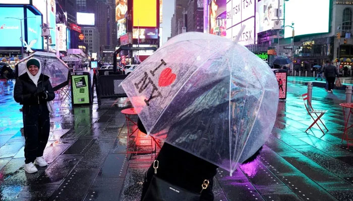 People carry umbrellas on Times Square in New York as the northeastern US is hit by bad weather. — AFP