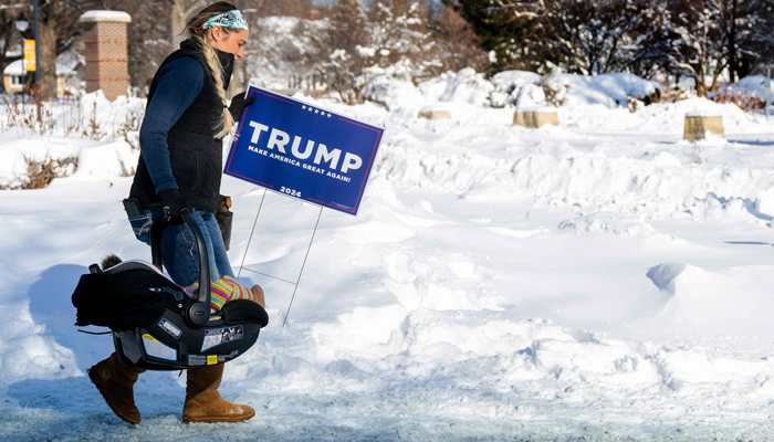 A supporter of former US President Donald Trump carries a baby and a Trump placard as she braves the below-zero temperatures to attend a rally in Indianola, Iowa, on January 14, 2024. — AFP