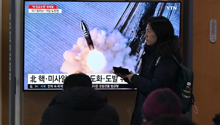 People watch a television screen showing a news broadcast with file footage of a North Korean missile test, at a railway station in Seoul on January 14, 2024. — AFP