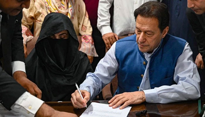 PTI founder Imran Khan along with his wife Bushra Bibi signs surety bonds for bail in various cases, at a registrars office in the high court, in Lahore on July 17, 2023. — AFP