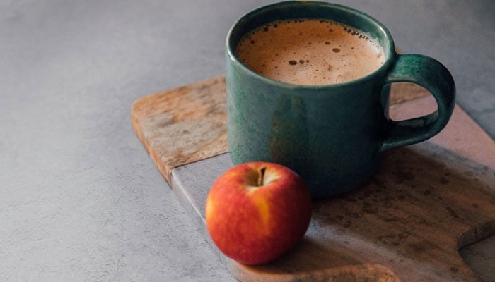 Image of an Apple and a cup of coffee side by side. — Coffee addiction